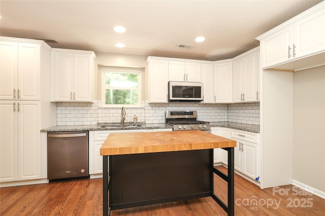 2011 Redwood Dr, Indian Trail, NC 28079 - kitchen featuring butcher block countertops, appliances with stainless steel finishes, white cabinetry, backsplash, and dark wood-style floors