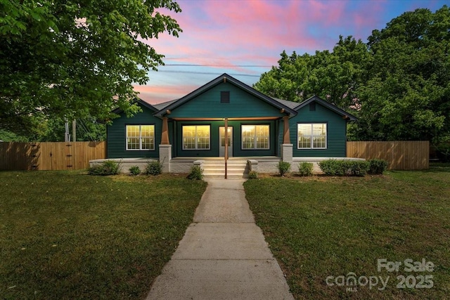 bungalow-style house with a front lawn, fence, and covered porch