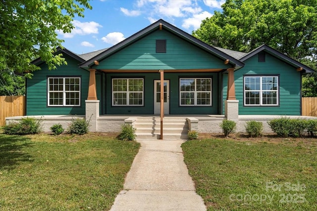 view of front of property featuring fence, covered porch, and a front yard