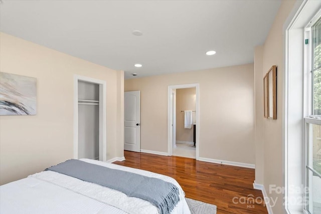 bedroom with wood finished floors, recessed lighting, baseboards, a closet, and ensuite bath