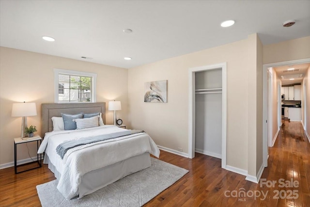 bedroom featuring baseboards, a closet, wood finished floors, and visible vents