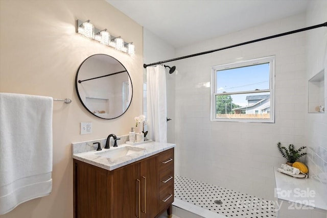 full bathroom featuring a tile shower and vanity