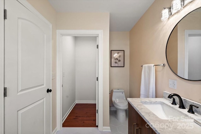 half bath featuring toilet, baseboards, tile patterned flooring, and vanity