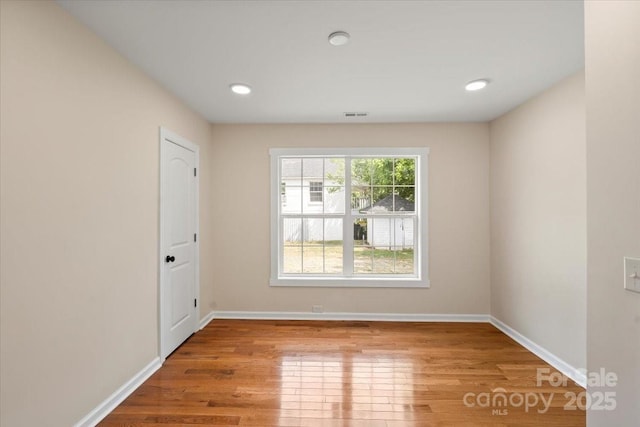 empty room featuring recessed lighting, baseboards, visible vents, and wood finished floors