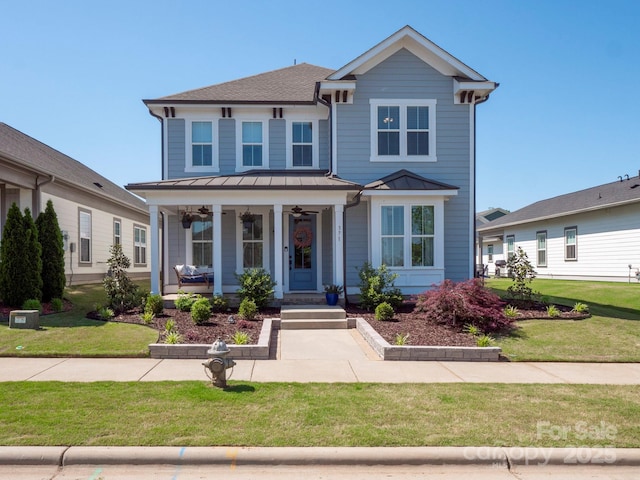 view of front facade featuring covered porch, a standing seam roof, a ceiling fan, metal roof, and a front lawn