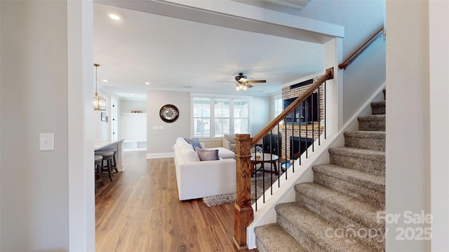 living room featuring ceiling fan, wood finished floors, stairway, baseboards, and recessed lighting