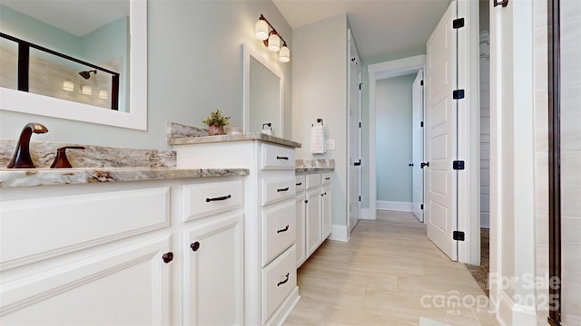 bathroom with vanity, baseboards, and a shower stall