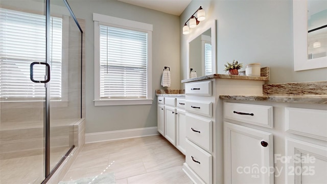 bathroom featuring a healthy amount of sunlight, baseboards, and a shower stall