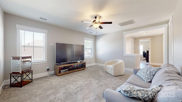 carpeted living area with baseboards, ceiling fan, and visible vents