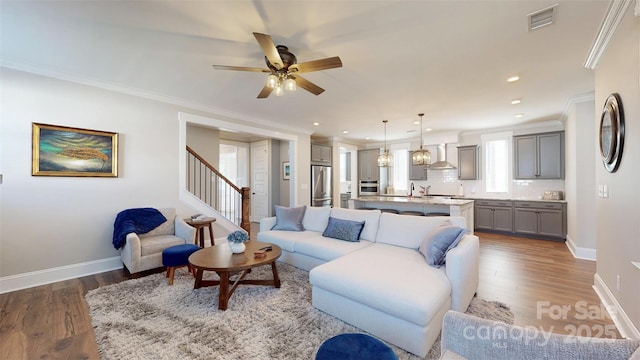 living room featuring crown molding, a ceiling fan, baseboards, and wood finished floors