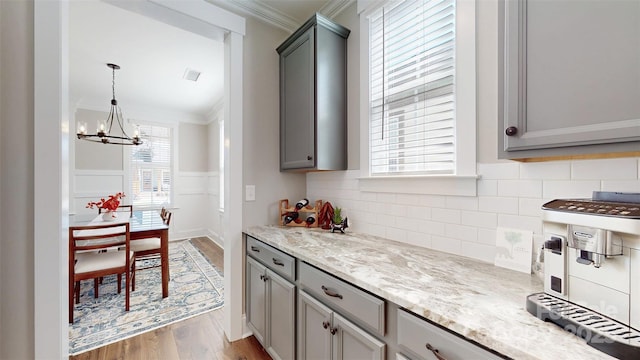 kitchen with gray cabinets, ornamental molding, and wood finished floors