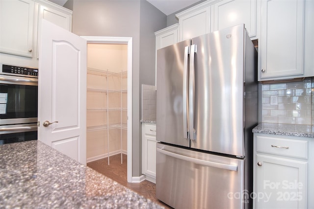 3073 Oliver Stanley Trl, Lancaster, SC 29720 - kitchen with decorative backsplash, wood finished floors, white cabinetry, dark stone countertops, and appliances with stainless steel finishes