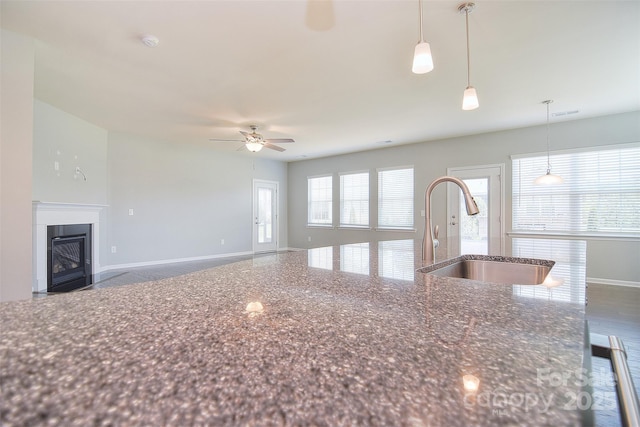3073 Oliver Stanley Trl, Lancaster, SC 29720 - kitchen with a ceiling fan, a sink, dark stone counters, a fireplace with flush hearth, and baseboards