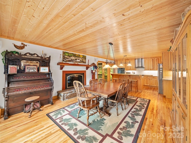 dining area featuring light wood-type flooring, wood ceiling, and a glass covered fireplace