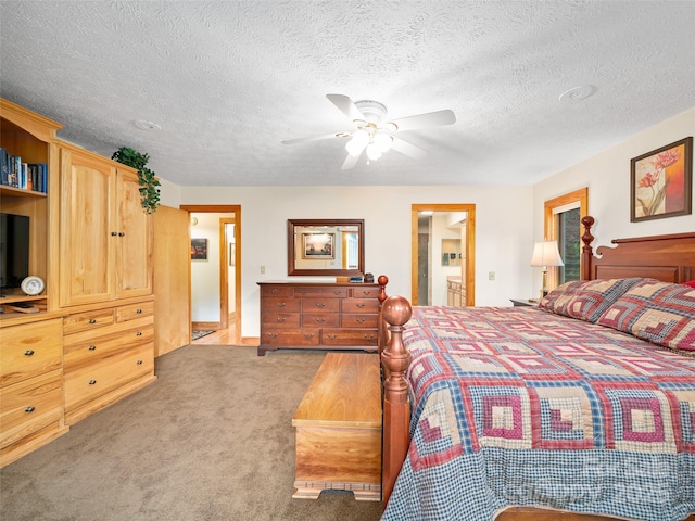 bedroom with a ceiling fan, baseboards, a textured ceiling, carpet flooring, and ensuite bath