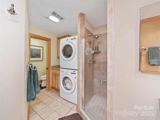 laundry area with light tile patterned floors, laundry area, stacked washer and dryer, and visible vents