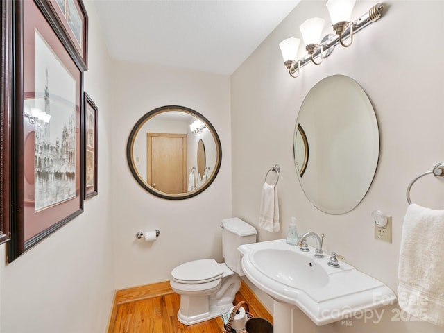 bathroom with baseboards, toilet, and wood finished floors