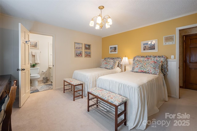 69 Forest Rd, Asheville, NC 28803 - bedroom with a chandelier, light carpet, ornamental molding, connected bathroom, and a decorative wall