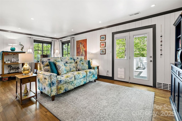 living area with crown molding, wood finished floors, and visible vents