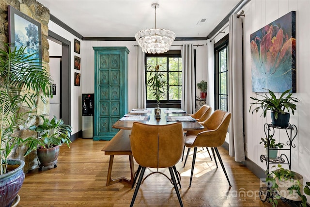 dining room featuring visible vents, crown molding, wood finished floors, baseboards, and an inviting chandelier