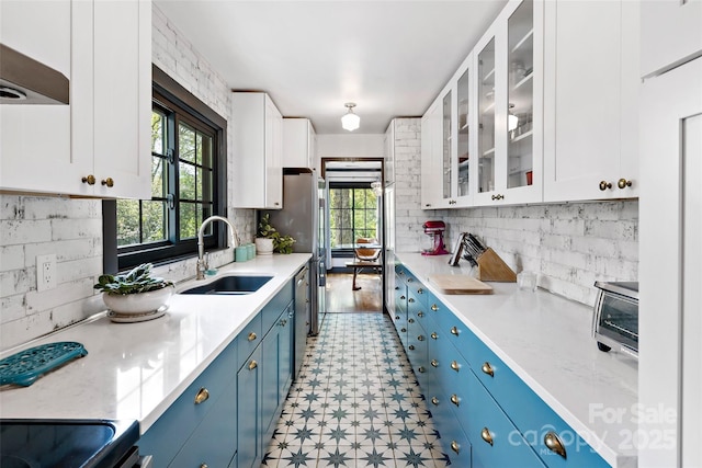kitchen featuring white cabinetry, blue cabinetry, a sink, and light floors