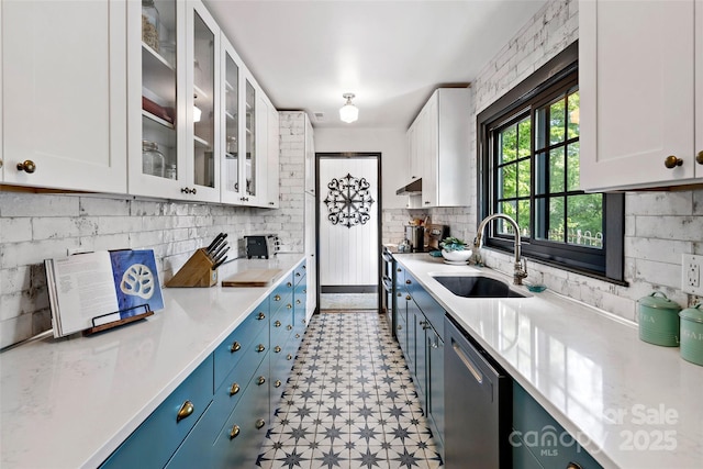 kitchen featuring stainless steel dishwasher, a sink, light countertops, white cabinets, and light floors