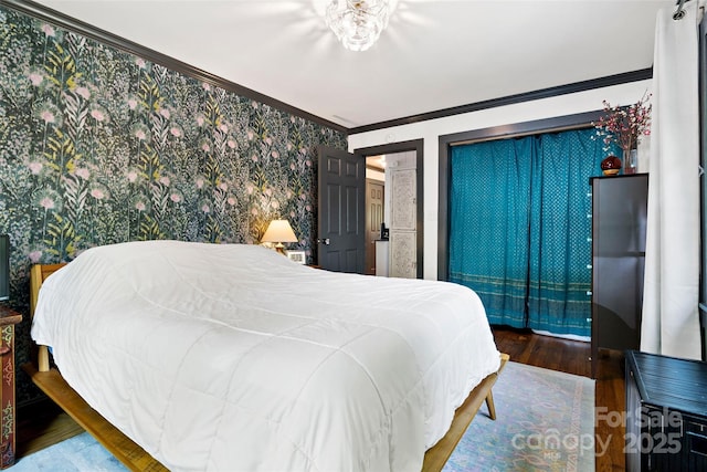 bedroom with crown molding, wallpapered walls, and wood finished floors