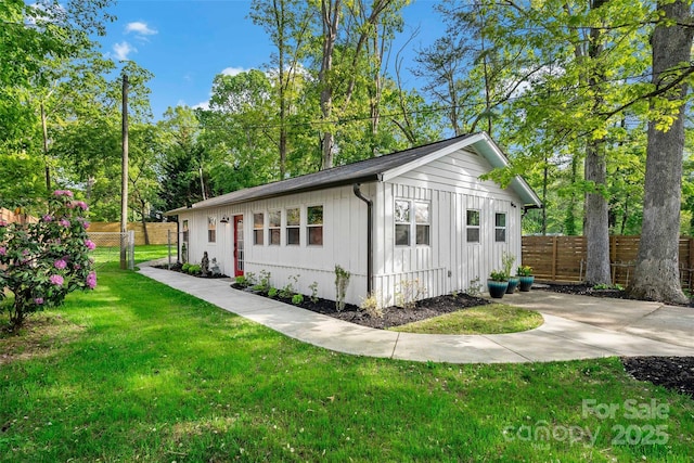 view of front facade with a front lawn, board and batten siding, and fence