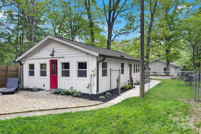 view of front facade featuring board and batten siding, fence, and a front lawn