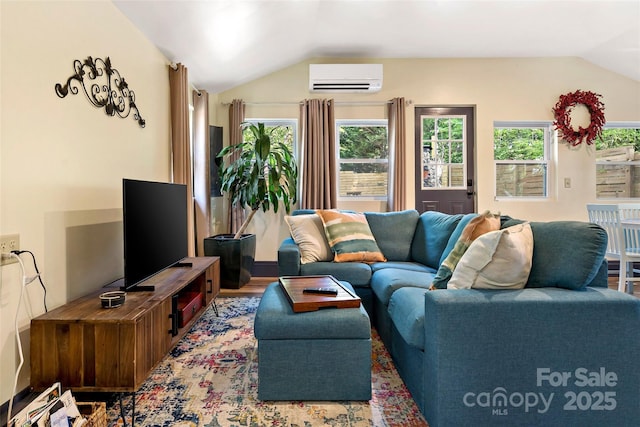 living area with plenty of natural light, wood finished floors, lofted ceiling, and a wall mounted air conditioner