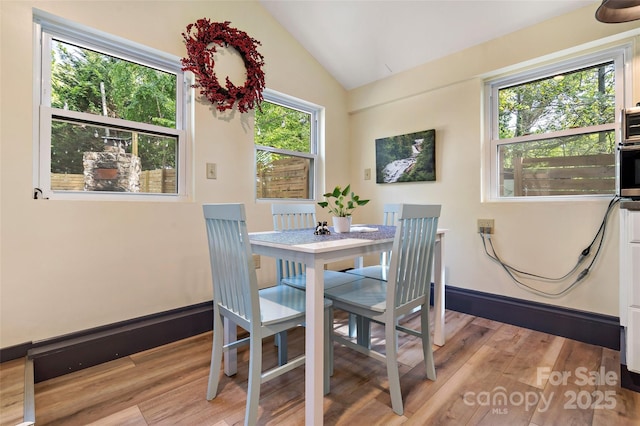 dining room with light wood finished floors and lofted ceiling