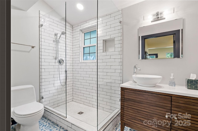 bathroom with vanity, a tile shower, and toilet
