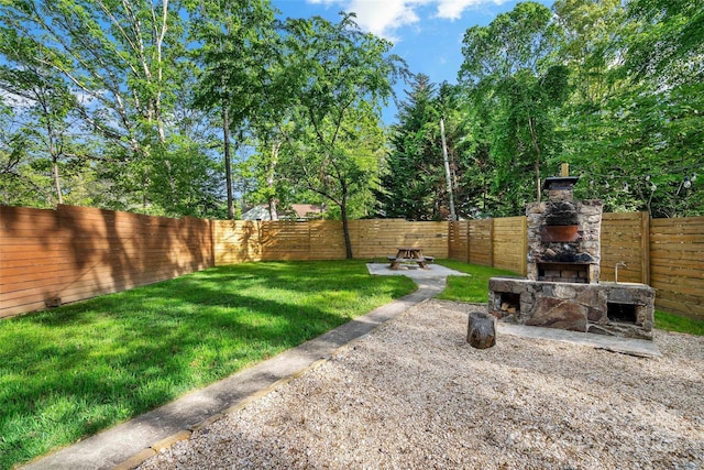 view of yard with a fenced backyard, a patio, and an outdoor stone fireplace