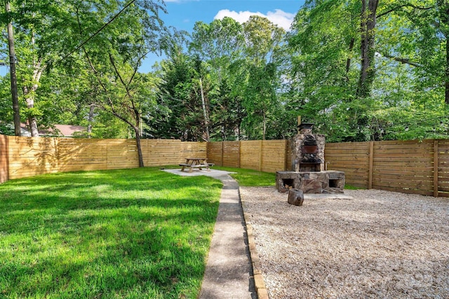 view of yard with a fenced backyard and an outdoor stone fireplace