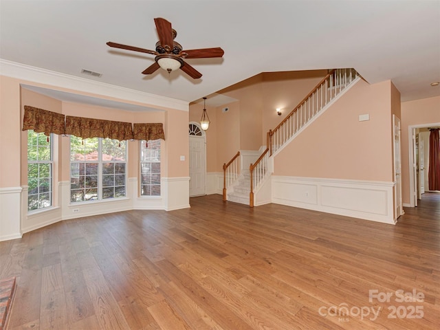2825 Redfield Dr, Charlotte, NC 28270 - unfurnished living room featuring ceiling fan, stairs, wood finished floors, a decorative wall, and a wainscoted wall