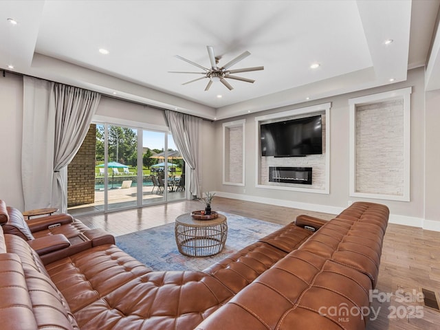 4315 Hartis Grove Church Rd, Indian Trail, NC 28079 - living room featuring ceiling fan, wood finished floors, recessed lighting, a glass covered fireplace, and a raised ceiling