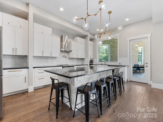 4315 Hartis Grove Church Rd, Indian Trail, NC 28079 - kitchen with wall chimney range hood, dark countertops, backsplash, a kitchen bar, and dark wood finished floors