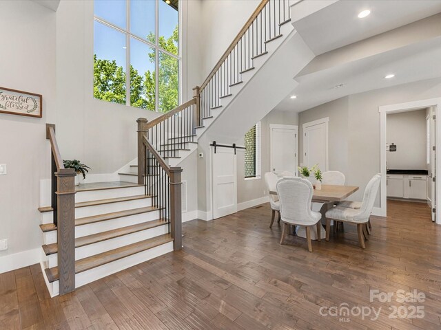 4315 Hartis Grove Church Rd, Indian Trail, NC 28079 - dining area featuring stairs, wood finished floors, a barn door, recessed lighting, and a towering ceiling