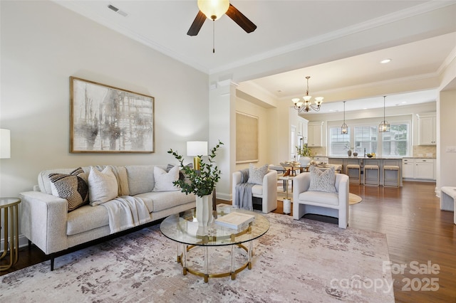 living room with wood finished floors, crown molding, a chandelier, and ceiling fan