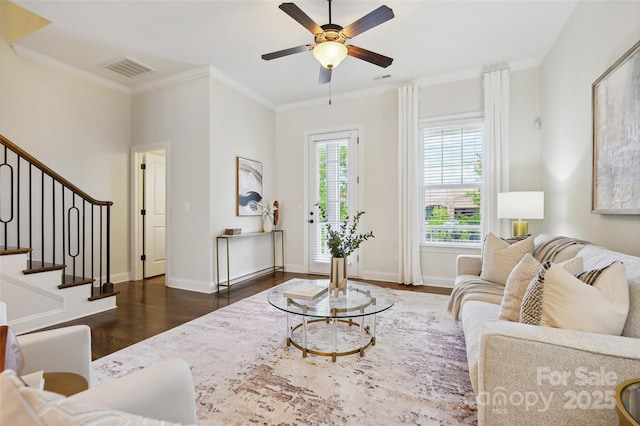 living area featuring dark wood-type flooring, a ceiling fan, stairs, crown molding, and baseboards