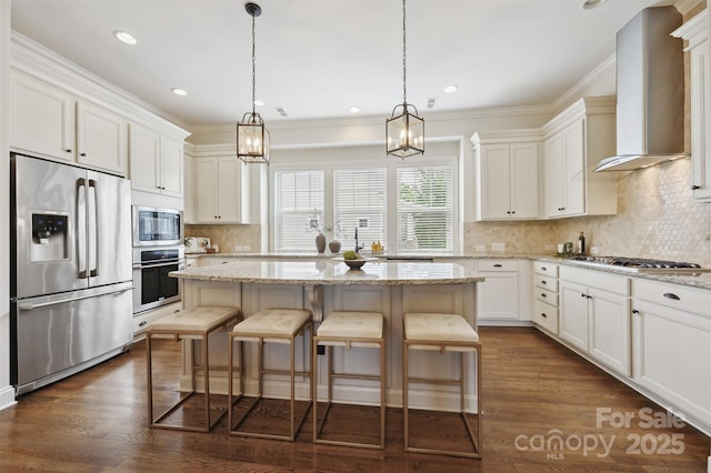 kitchen featuring appliances with stainless steel finishes, wall chimney exhaust hood, decorative backsplash, white cabinets, and ornamental molding