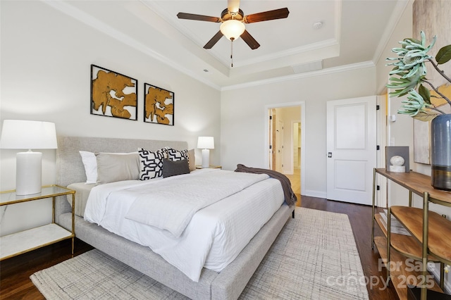 bedroom featuring a tray ceiling, wood finished floors, ornamental molding, and a ceiling fan