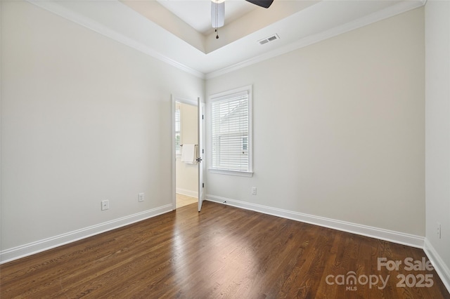 spare room featuring baseboards, a ceiling fan, wood finished floors, ornamental molding, and a tray ceiling