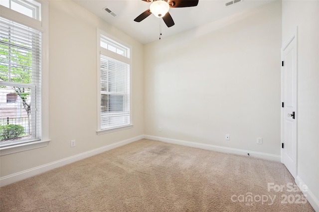 carpeted empty room with a ceiling fan and baseboards