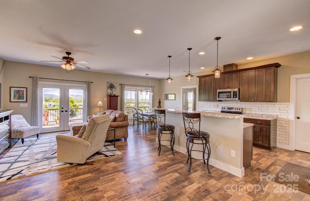 kitchen featuring a ceiling fan, a kitchen bar, open floor plan, decorative backsplash, and stainless steel appliances