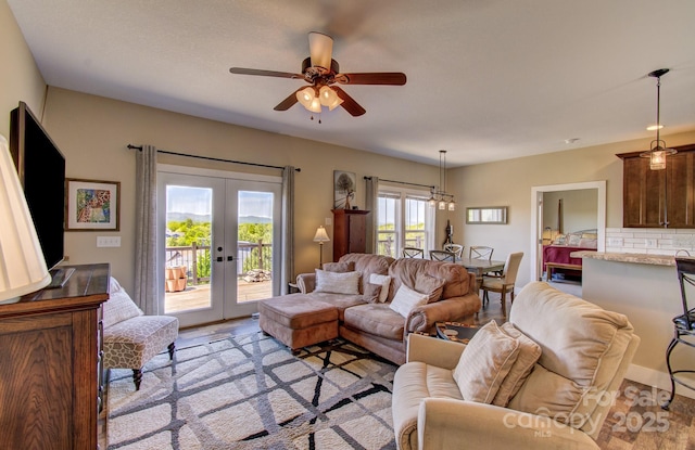living area featuring light wood-type flooring, french doors, and ceiling fan