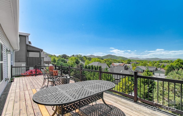 wooden deck with outdoor dining area, a mountain view, and a residential view