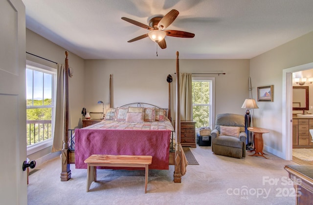 bedroom featuring light colored carpet, ensuite bath, baseboards, and multiple windows