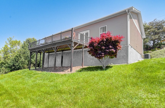 back of property featuring a wooden deck, cooling unit, and a lawn