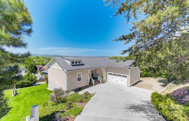 view of front of property with concrete driveway, metal roof, a garage, and a front lawn